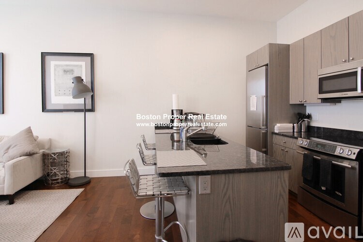 A modern kitchen with a dining table and chairs, and a fridge and oven built into the cabinetry.