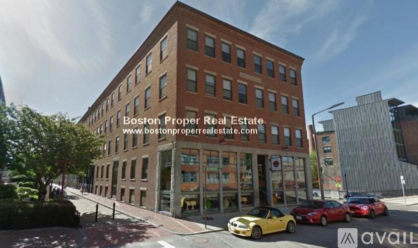 A street view of a building with the sign "Boston Proper Real Estate" and the website "www.bostonproperrealestate.com" on it.