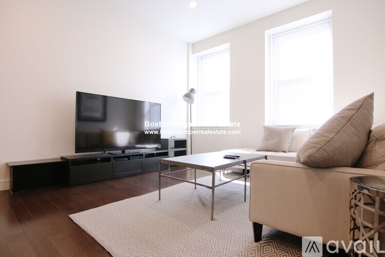 A modern living room with a flat screen TV, a coffee table, and a sofa.