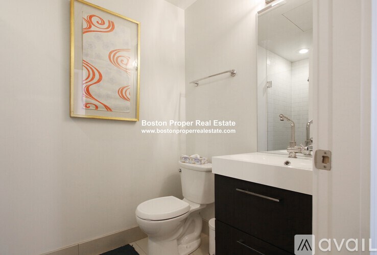 A bathroom with a toilet, sink, and a framed picture on the wall.