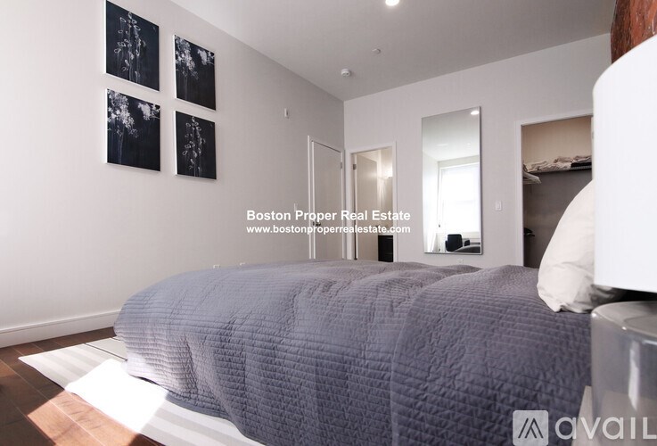 A bedroom with a bed, a mirror, and a painting on the wall.