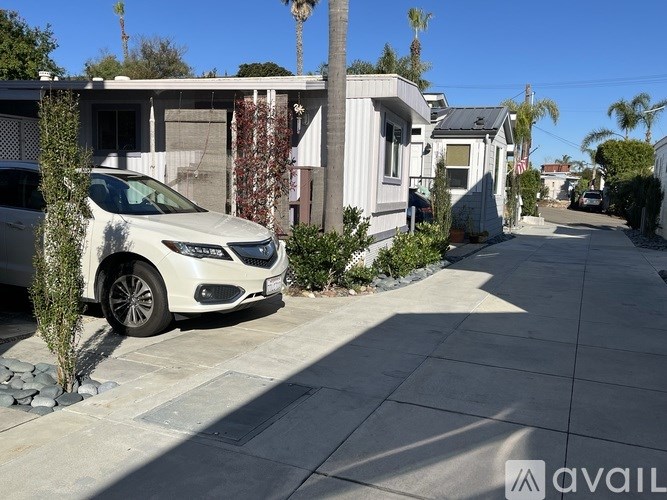 A white car is parked on a driveway in front of a house.