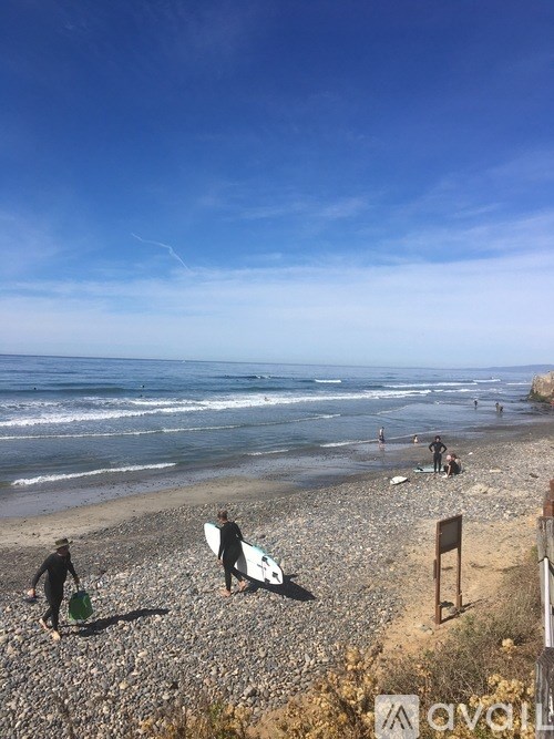 A beach scene with people in wetsuits and surfboards.