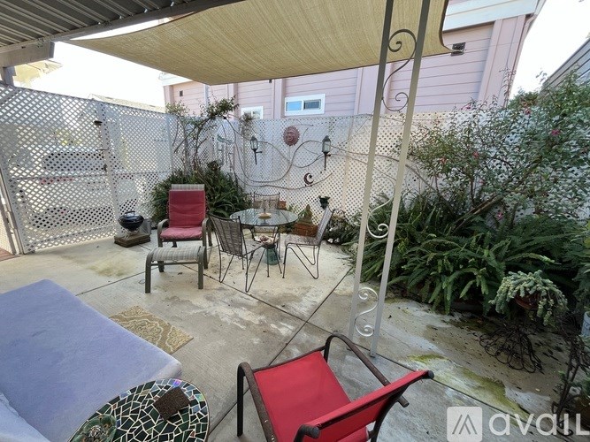 A patio with a table, chairs, and plants.