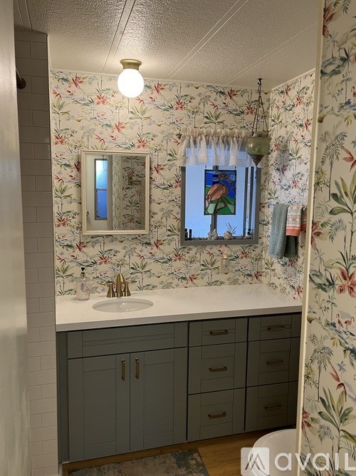 A bathroom with floral wallpaper and a white sink.