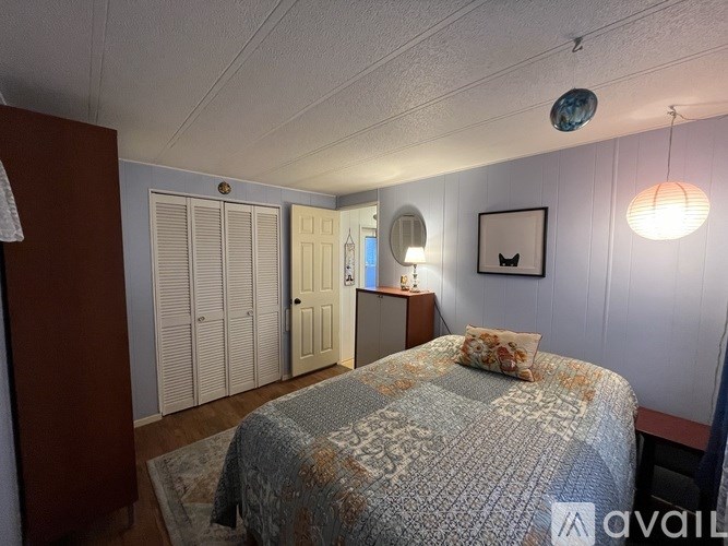 A bedroom with a bed, a dresser, and a lamp.