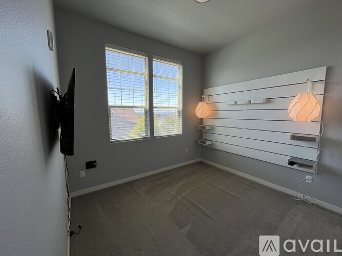 A room with a television, a window, and a wall-mounted shelf.
