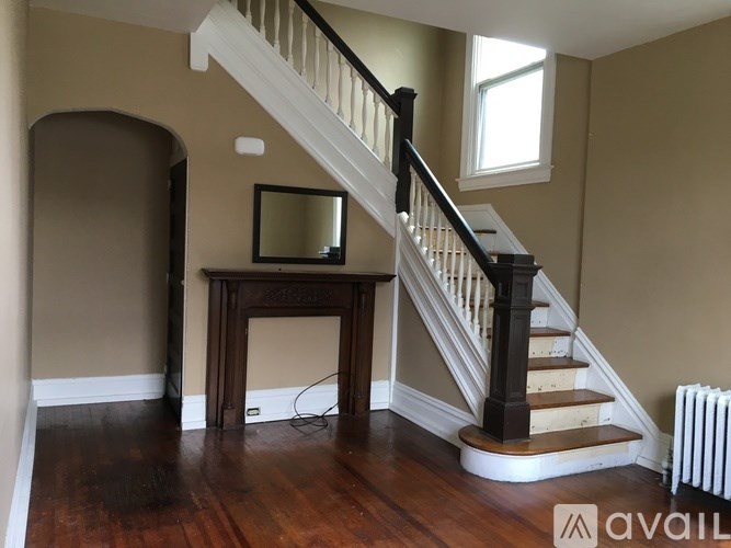 A staircase with a wooden banister and a mirror on a table.