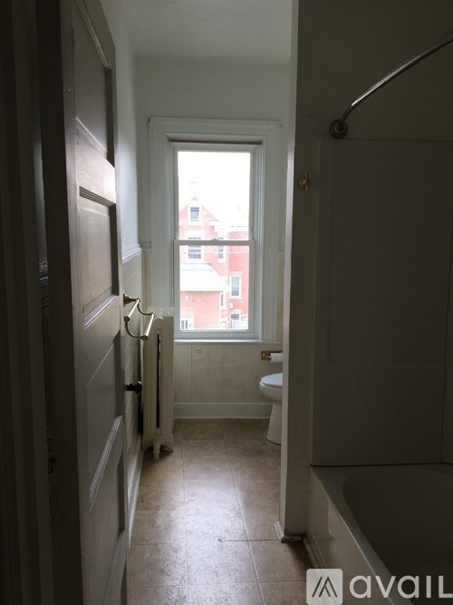 A bathroom with a toilet, sink and a window.