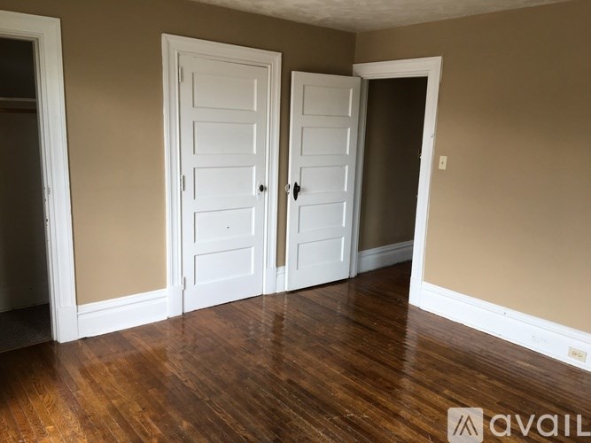 A room with two white doors and wooden floors.
