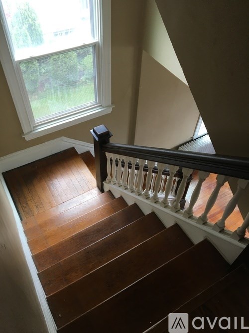 A staircase with a black railing and wooden steps leading to a window.