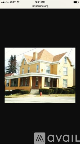 A large yellow house with a brown roof and a tree in front.