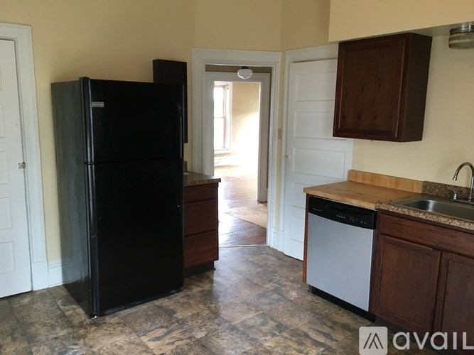 A black fridge in a kitchen with a marble floor.