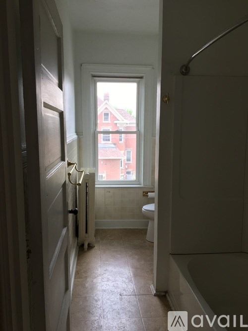 A bathroom with a toilet, sink and a window.