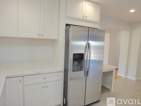 A stainless steel refrigerator in a kitchen with white cabinets.