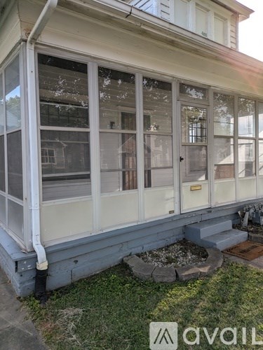 A white house with a large window and a small garden in front.