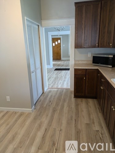 A kitchen with wooden cabinets and a microwave on the counter.