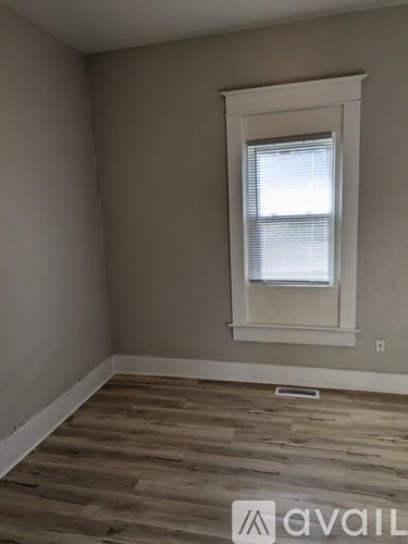 A room with a window and wooden flooring.