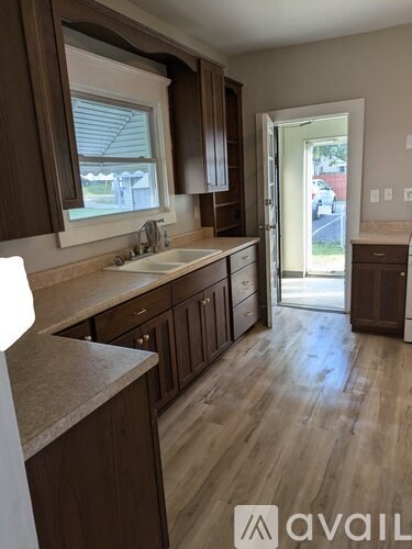 A kitchen with brown cabinets and a window.
