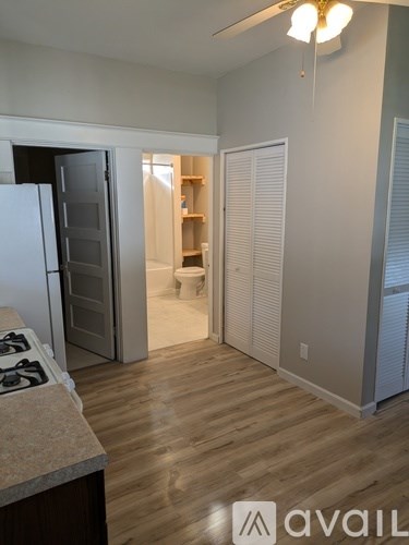 A kitchen with a white fridge and a wooden floor.