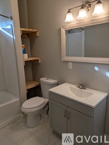 A bathroom with a toilet, sink, and mirror.