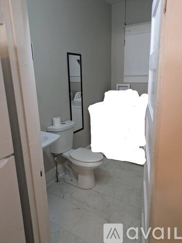 A bathroom with a toilet, sink, and mirror.