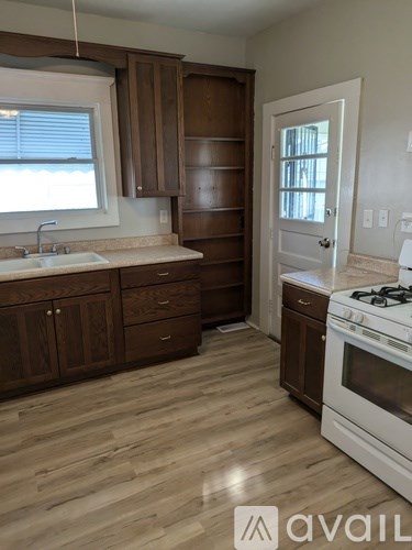 A kitchen with wooden cabinets and a white stove top oven.