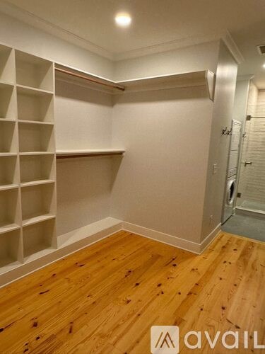 A room with wooden floors and white shelving units.