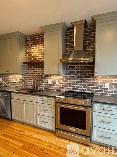 A kitchen with a brick wall and wooden floors.