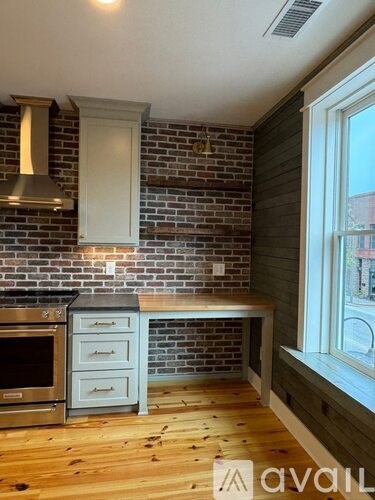 A kitchen with a brick wall and wooden flooring.