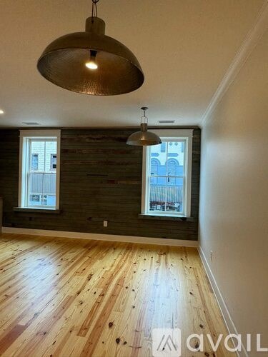 A room with wooden floors and a large pendant light hanging from the ceiling.