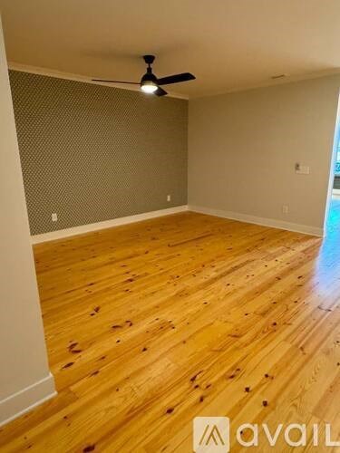 A room with wooden flooring and a ceiling fan.