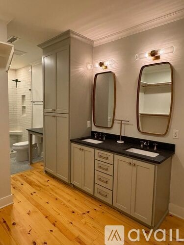 A bathroom with wooden floors and a vanity with two sinks.