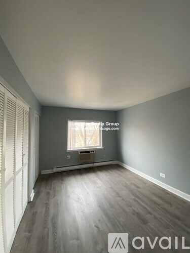 A room with wooden floors and a window with blinds.