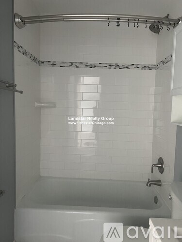 A white tiled bathroom with a glass shower door.