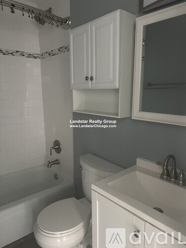 A white toilet in a bathroom with a white tub and sink.