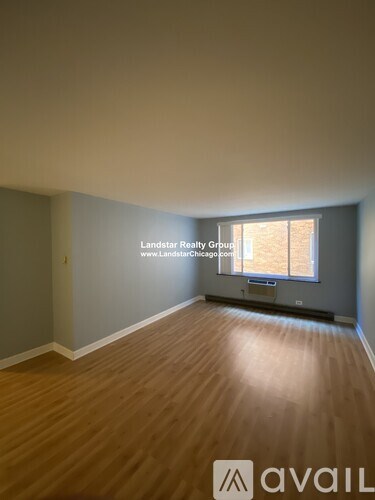 A room with wooden flooring and a window with blinds.