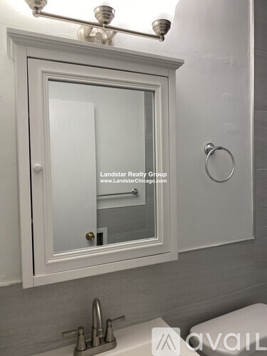 A white bathroom cabinet with a mirror and a light above it.