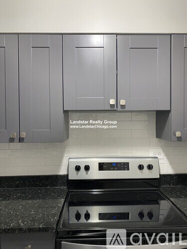 A stove top oven in a kitchen with grey cabinets.