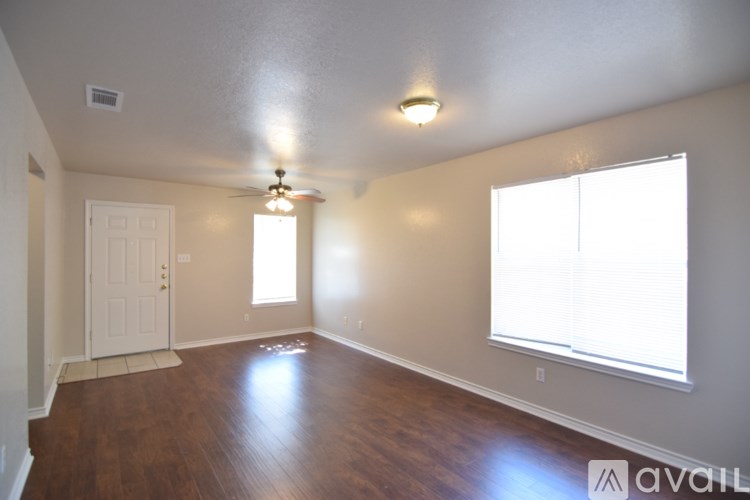 A room with a white door, a window with blinds, and a ceiling fan.