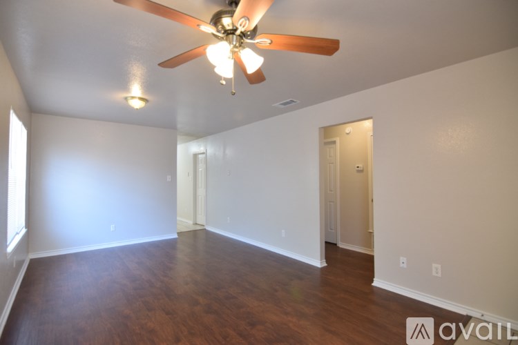 A room with a ceiling fan and wooden floors.