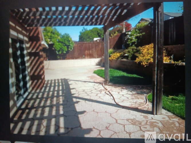 A patio with a wooden pergola and a stone walkway.