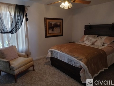 A bedroom with a bed, chair, and painting on the wall.