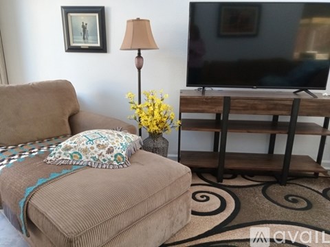 A living room with a couch, a lamp, a TV and a flower vase.