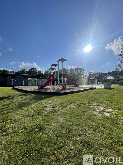 A playground with a red slide and a sunny sky.