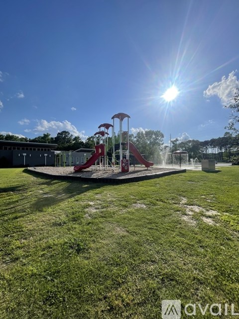 A playground with a red slide and a sunny sky.