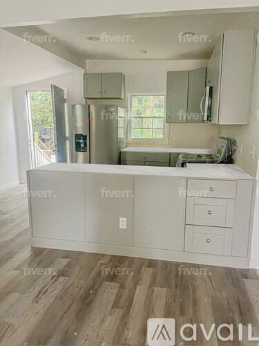 A kitchen with white cabinets and a wooden floor.