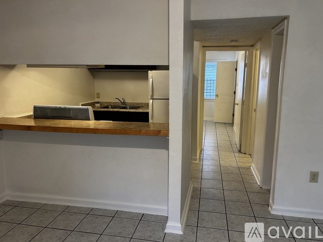 A kitchen with white walls and a tiled floor.