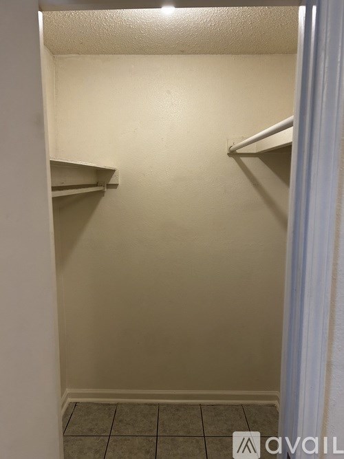 A small, empty room with a tiled floor and two shelves on the wall.