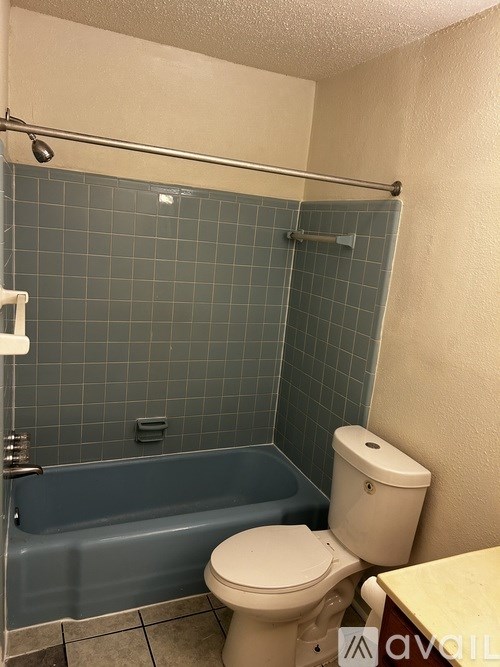 A bathroom with a toilet, tub, and towel rack.